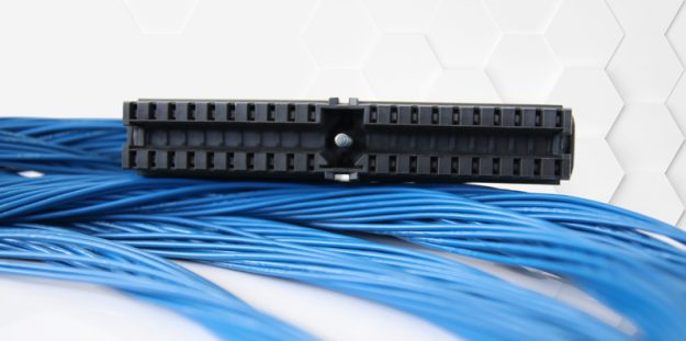 Ein schwarzer Fronststecker von Simatic liegt auf aufgewickelten blauen Kabeln