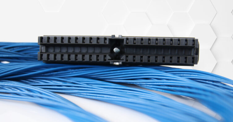 Ein schwarzer Fronststecker von Simatic liegt auf aufgewickelten blauen Kabeln