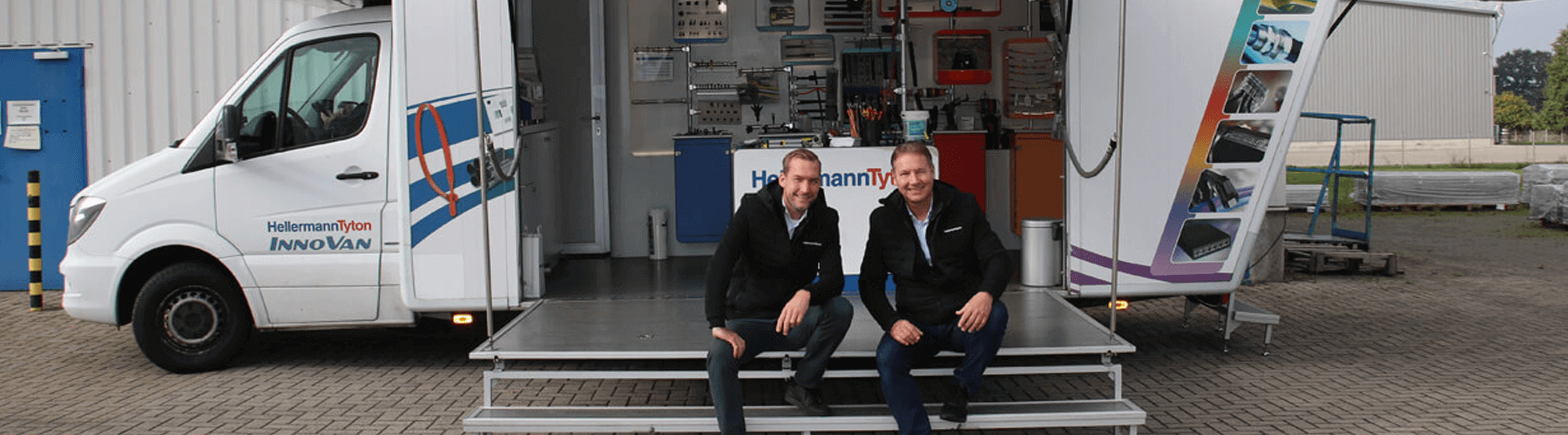 Zwei Personen sitzen auf der erhöhten Ebene eines Busses der Firma Hellermann