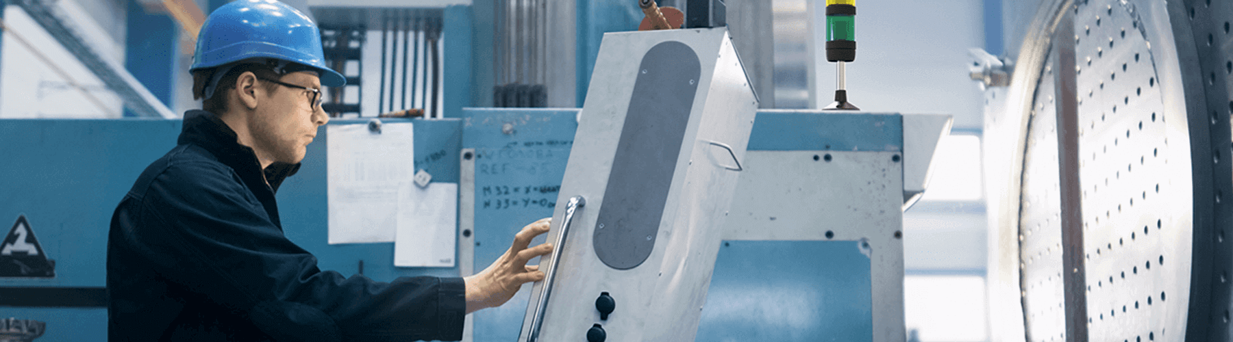 Ein Arbeiter in einer Halle. Er schiebt ein Gerät