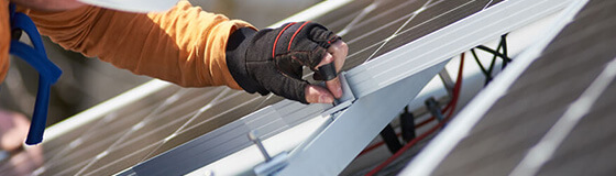 Ein Mann mit Sicherheitshelm arbeitet an einer PV-Unterkonstruktion