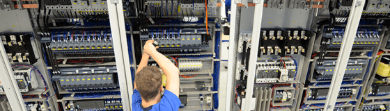Ein Mann schraubt an einem Schaltschrank.